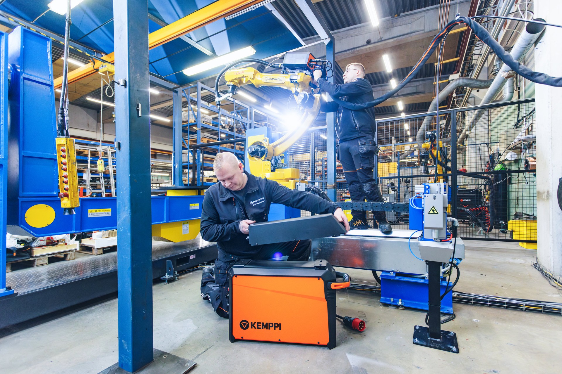 In this photo the managing director Jani Matikainen with his colleague is integrating a Kemppi AX MIG Welder to a robot.